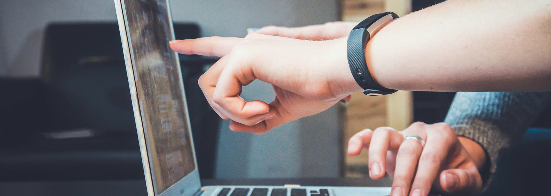 Image of two sets of hands pointing to a computer laptop screen. Stock image from Unsplash. (John Schnobrich)